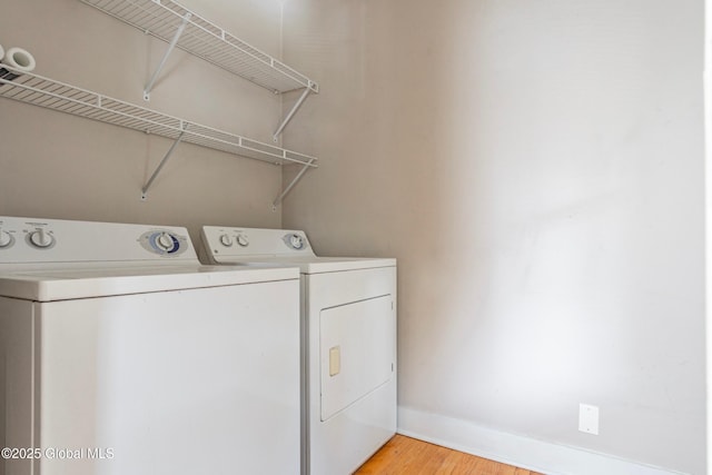 clothes washing area featuring washing machine and clothes dryer and light hardwood / wood-style flooring