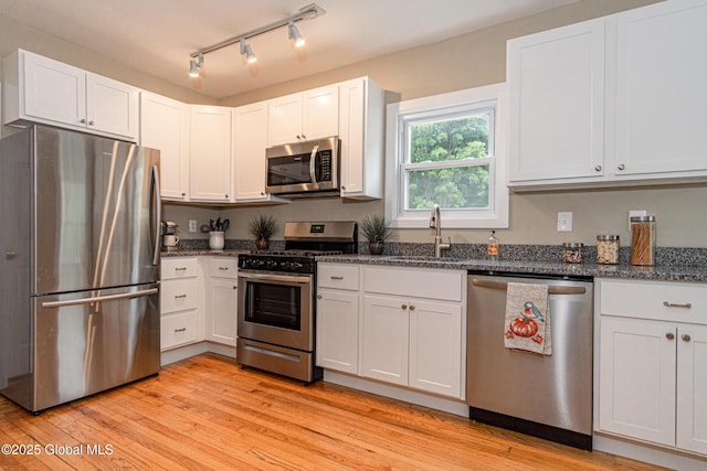 kitchen featuring white cabinetry, appliances with stainless steel finishes, sink, and light wood-type flooring