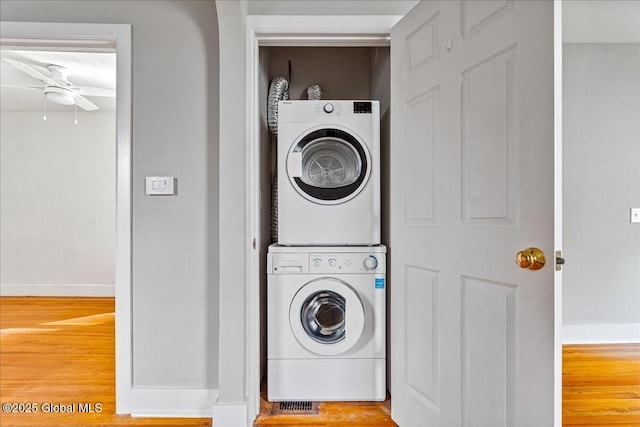 laundry room with stacked washer / drying machine and hardwood / wood-style floors