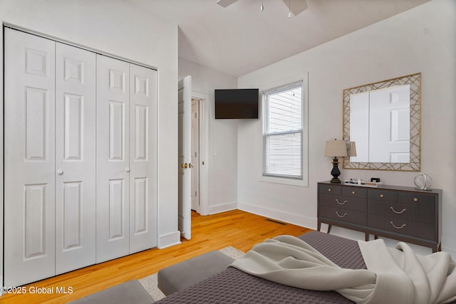 bedroom featuring vaulted ceiling, ceiling fan, light wood-type flooring, and a closet