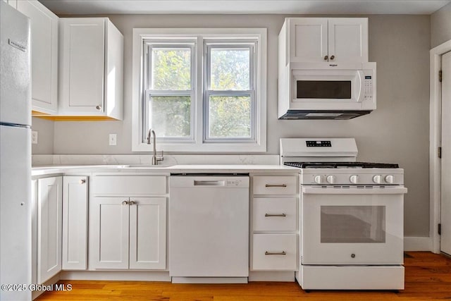 kitchen with sink, white cabinets, white appliances, and light hardwood / wood-style floors