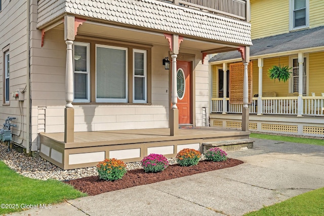 view of exterior entry with a balcony and covered porch