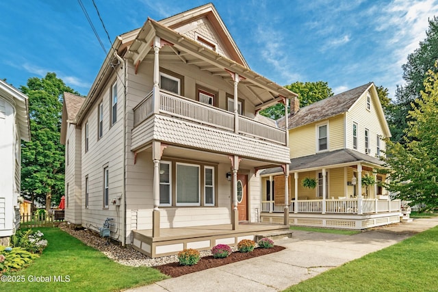 view of front of home with a porch, a balcony, and a front yard