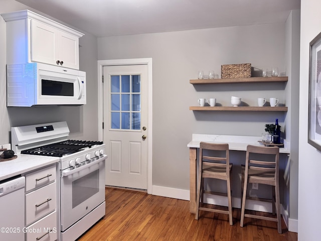 kitchen with white cabinets, white appliances, and light hardwood / wood-style floors