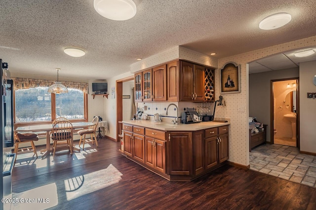 kitchen featuring dark hardwood / wood-style flooring, sink, hanging light fixtures, and a textured ceiling