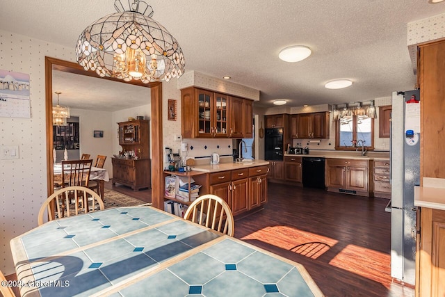 dining space featuring dark wood-type flooring, sink, a textured ceiling, and an inviting chandelier