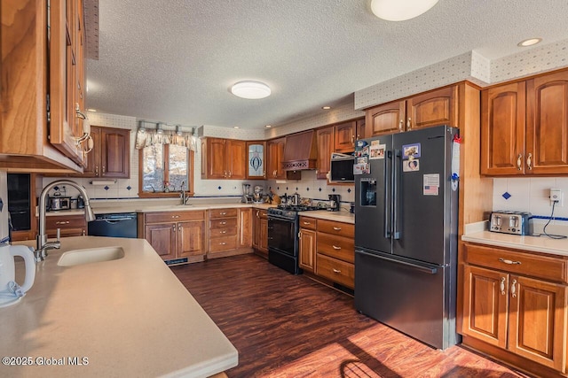 kitchen featuring sink, wall chimney range hood, high end fridge, dark hardwood / wood-style flooring, and gas range