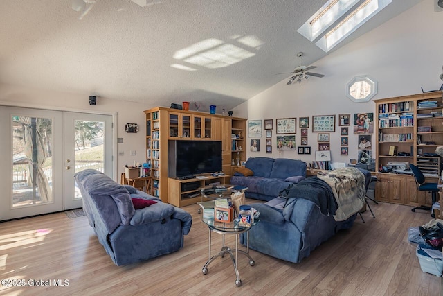 living room featuring lofted ceiling with skylight, french doors, and light wood-type flooring