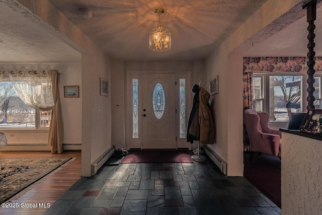 entrance foyer featuring an inviting chandelier, a wealth of natural light, and a baseboard radiator