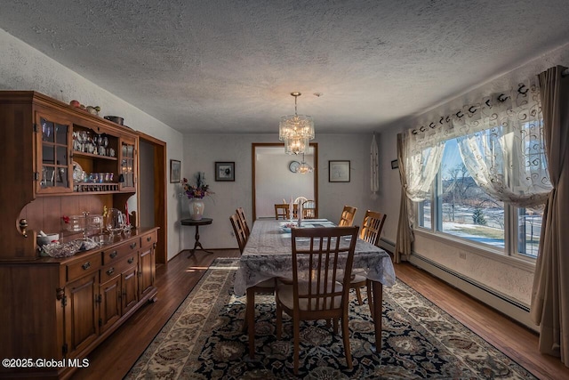 dining room with dark wood-type flooring, a textured ceiling, a notable chandelier, and baseboard heating