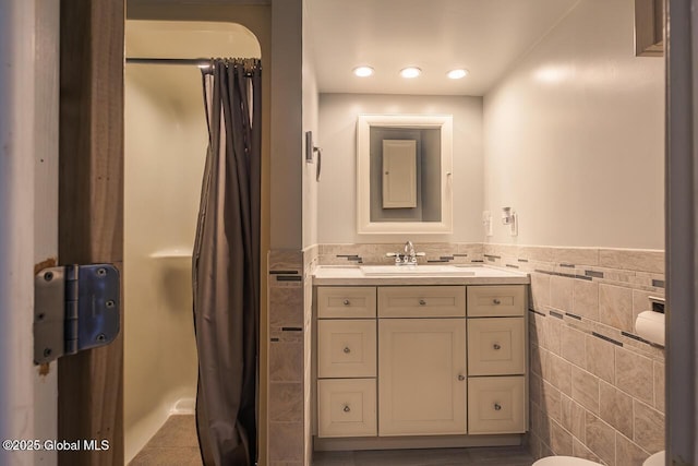 bathroom featuring vanity and tile walls