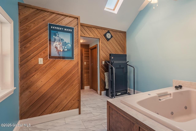 bathroom with a washtub, ceiling fan, wooden walls, and vaulted ceiling with skylight