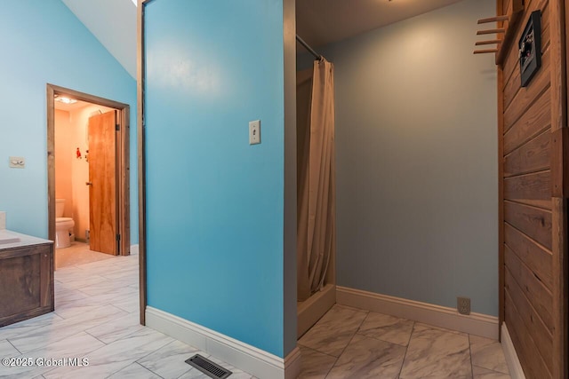 bathroom with walk in shower, vaulted ceiling, vanity, and toilet