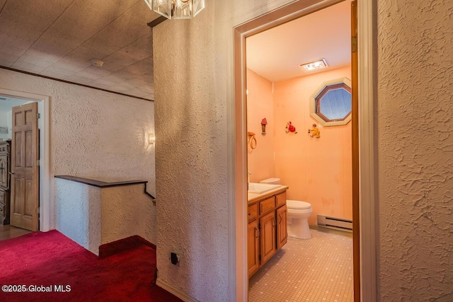 bathroom with vanity, baseboard heating, and toilet