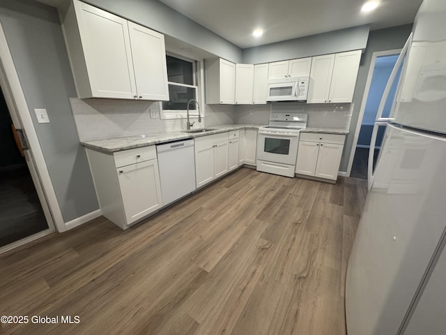 kitchen featuring sink, white cabinetry, light stone counters, dark hardwood / wood-style floors, and white appliances