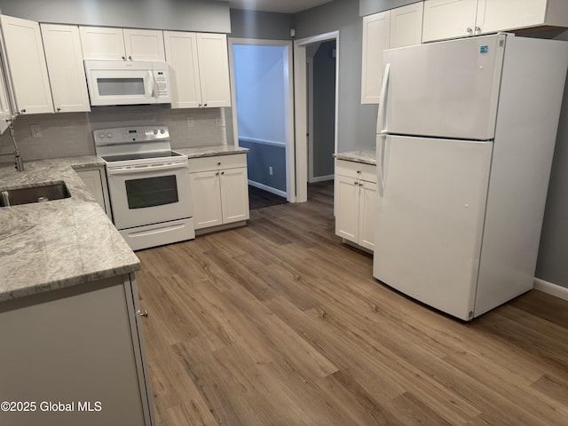 kitchen featuring sink, light stone counters, light wood-type flooring, white appliances, and white cabinets