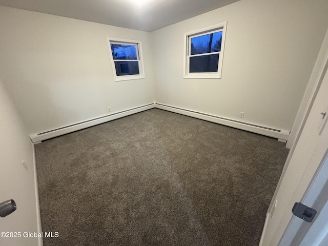 spare room featuring a baseboard heating unit and dark colored carpet