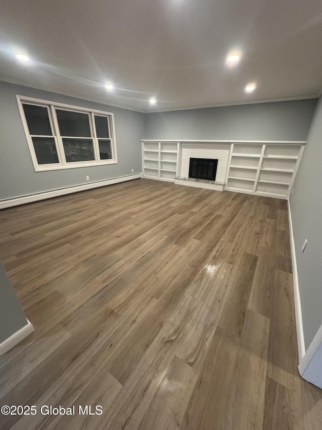 unfurnished living room featuring hardwood / wood-style flooring, a baseboard heating unit, and a fireplace