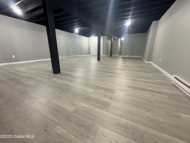 basement featuring hardwood / wood-style floors and a baseboard heating unit