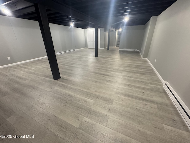 basement featuring a baseboard heating unit and hardwood / wood-style floors