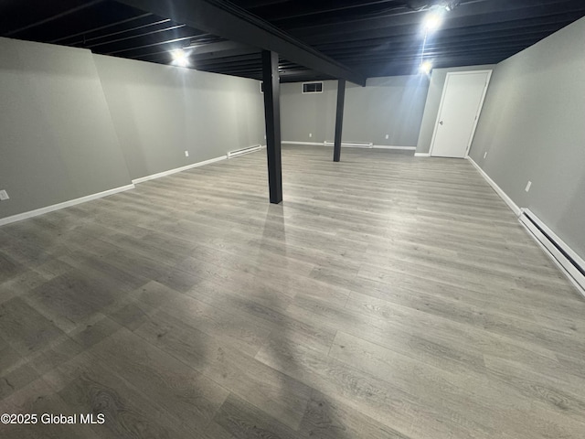 basement featuring wood-type flooring and baseboard heating