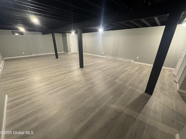 basement featuring a baseboard heating unit and wood-type flooring