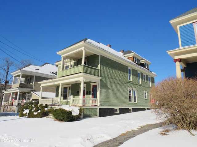 view of snowy exterior featuring a porch and a balcony