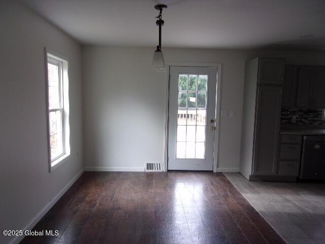 unfurnished dining area with a wealth of natural light and dark hardwood / wood-style floors