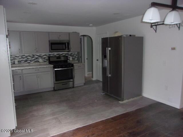 kitchen with tasteful backsplash, stainless steel appliances, and hardwood / wood-style flooring