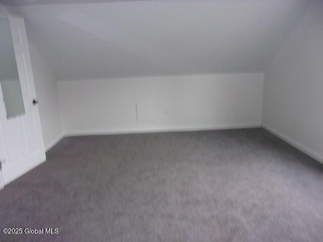 bonus room with lofted ceiling and dark carpet