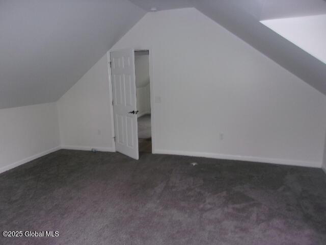 bonus room with vaulted ceiling and dark colored carpet