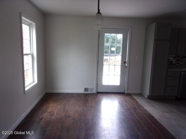 unfurnished dining area with dark wood-type flooring and plenty of natural light