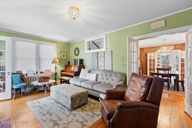 living room with hardwood / wood-style flooring, ornamental molding, and an inviting chandelier