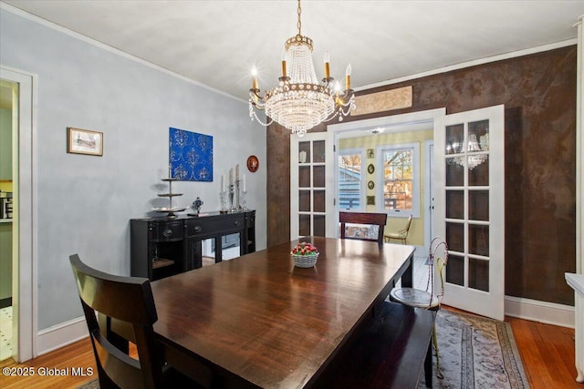 dining space with wood-type flooring, a chandelier, crown molding, and french doors