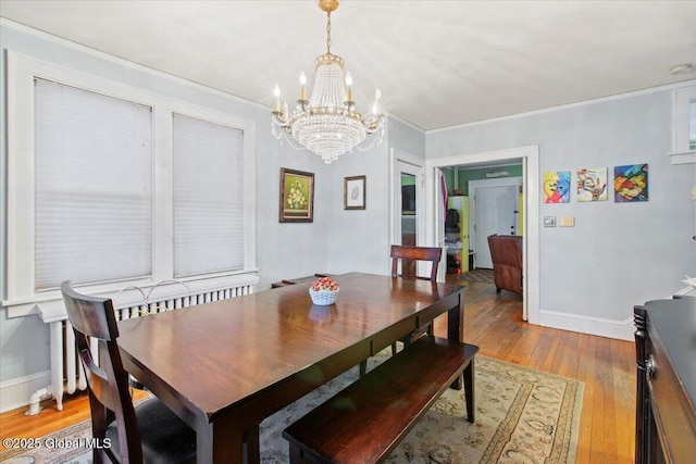 dining area featuring light hardwood / wood-style flooring, ornamental molding, and a chandelier