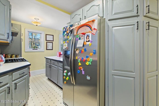 kitchen with stainless steel fridge, gray cabinets, and range hood