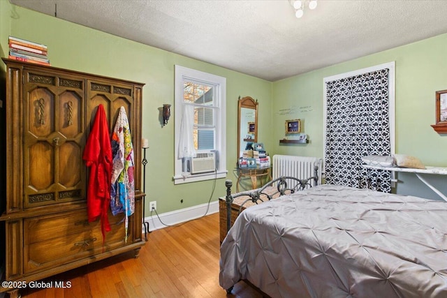 bedroom with cooling unit, radiator, hardwood / wood-style flooring, and a textured ceiling