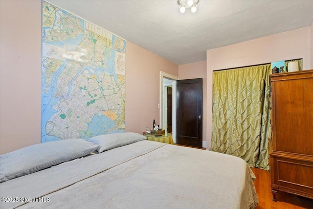 bedroom with wood-type flooring, a textured ceiling, and a closet