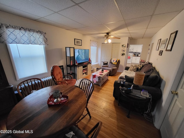 dining space with ceiling fan, a paneled ceiling, and light wood-type flooring