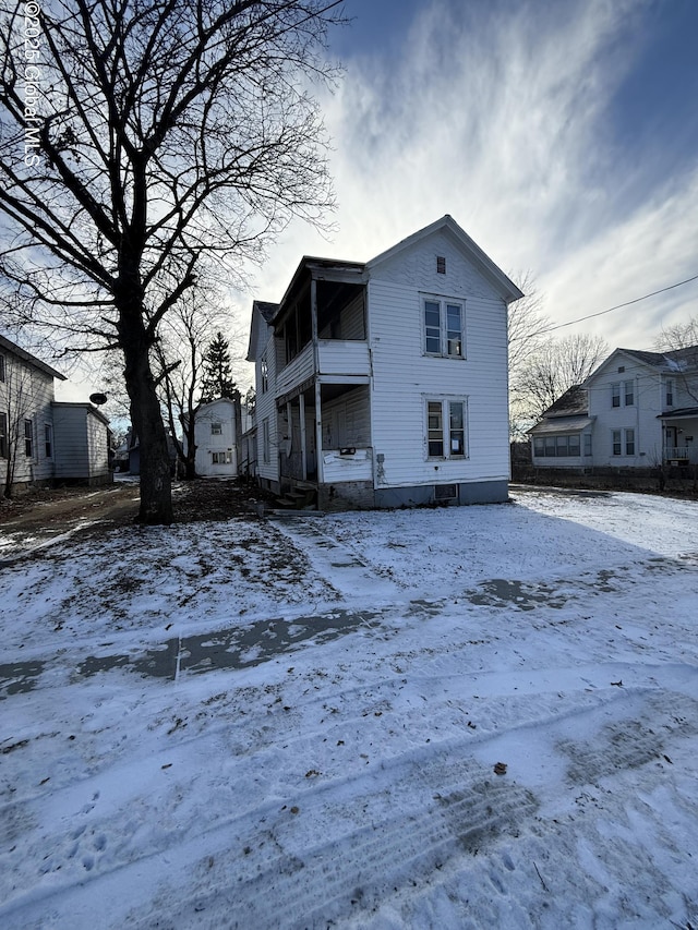 snow covered back of property with a balcony