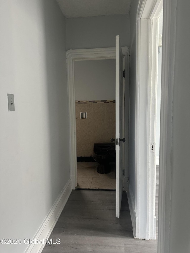 corridor with wood-type flooring and tile walls