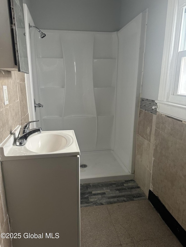 bathroom featuring tile walls, vanity, and walk in shower