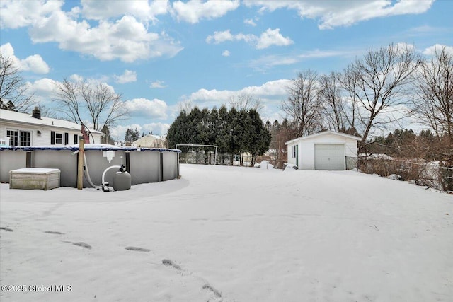 yard covered in snow with a garage and an outdoor structure