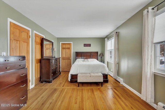 bedroom featuring a baseboard heating unit and light hardwood / wood-style floors