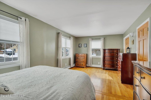 bedroom featuring light wood-type flooring and a baseboard heating unit