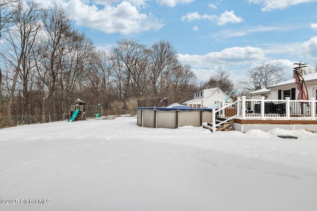 yard layered in snow with a pool side deck and a playground