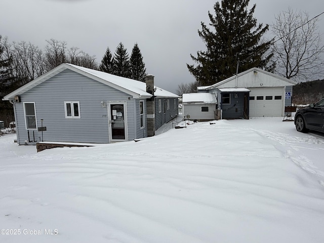 view of snowy exterior with a garage and an outdoor structure