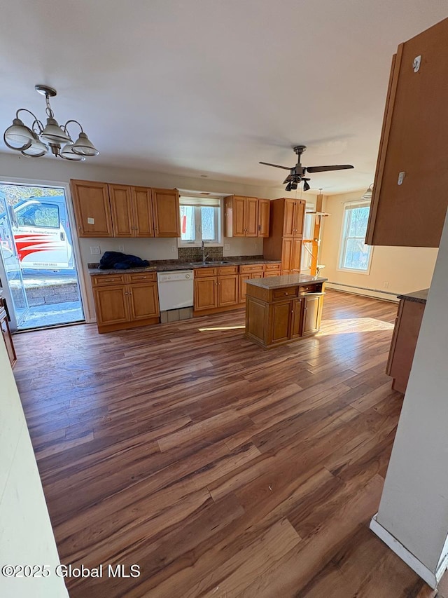 kitchen featuring sink, a center island, dark hardwood / wood-style floors, white dishwasher, and ceiling fan with notable chandelier