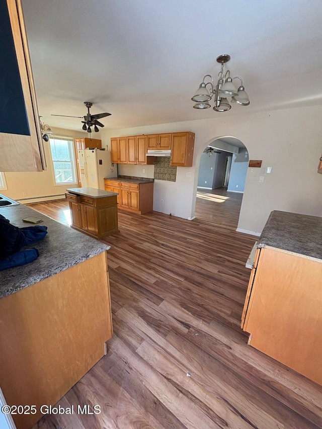 kitchen with dark hardwood / wood-style floors, ceiling fan with notable chandelier, pendant lighting, white refrigerator with ice dispenser, and a center island