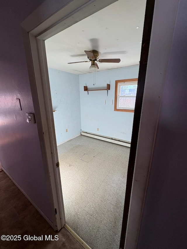 empty room featuring a baseboard heating unit and ceiling fan